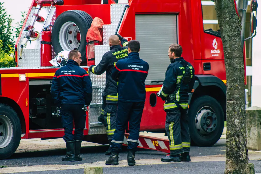 Officiers sapeurs-pompiers en réunion de gestion devant un camion rouge pour coordonner une intervention de secours.