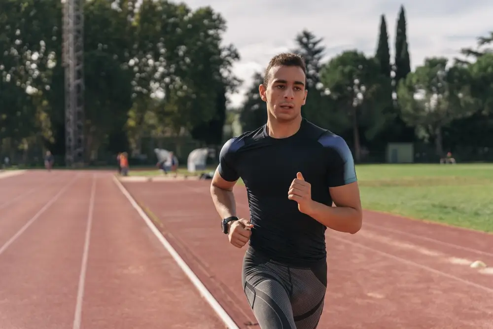 Candidat pompier effectuant un test d'endurance de course à pied sur une piste d'athlétisme.