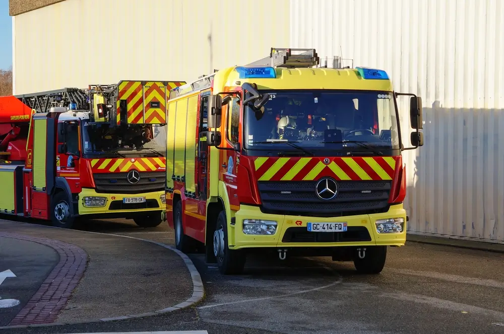 Véhicules d'intervention et de lutte contre l'incendie stationnés devant une caserne de sapeurs-pompiers.