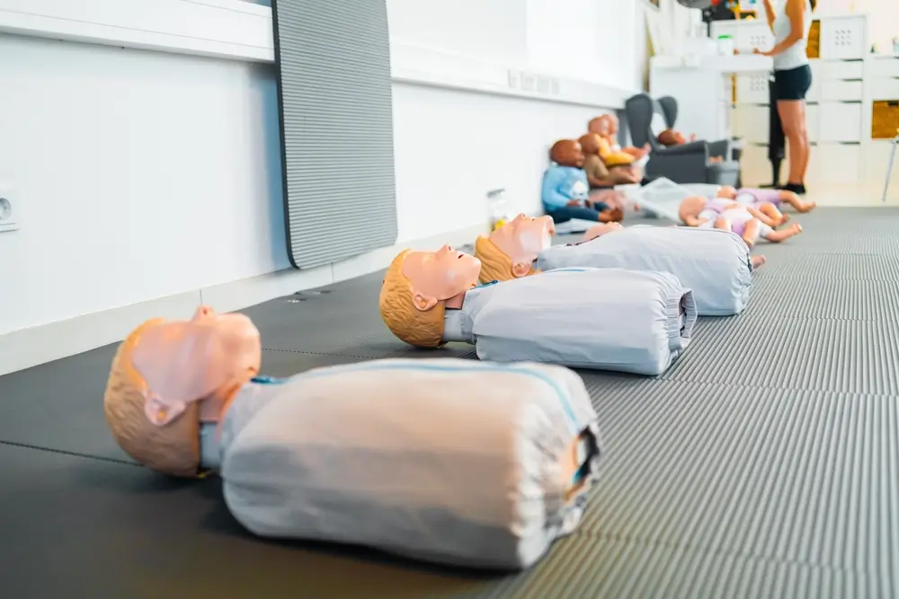 Mannequins de secourisme alignés dans une salle de formation de pompiers pour l'apprentissage des premiers secours.