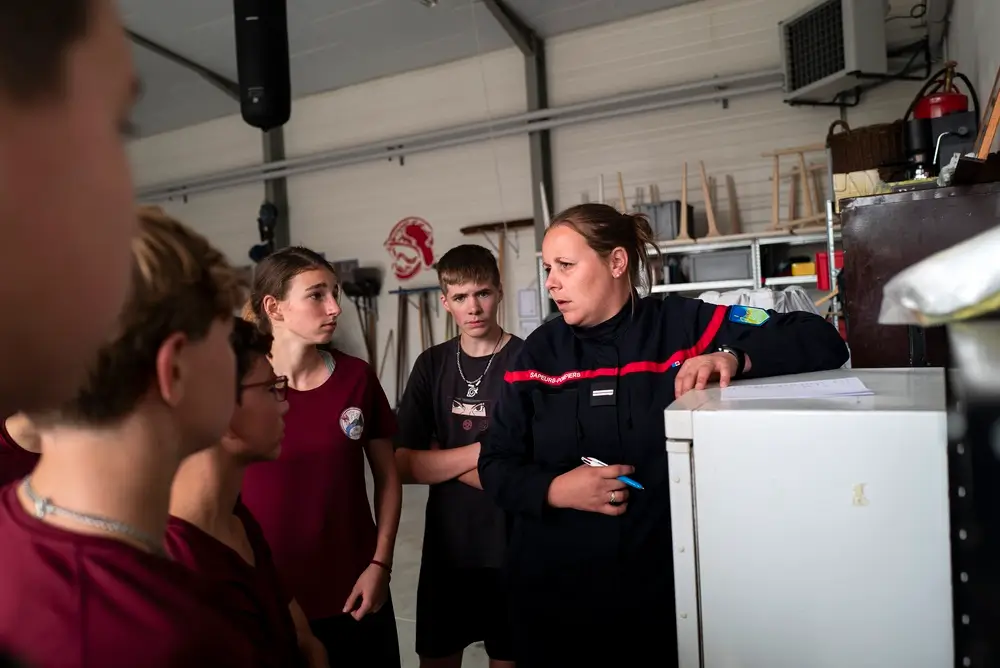 Une sapeur-pompier forme un groupe de jeunes recrues attentives lors d'une session d'instruction en caserne.